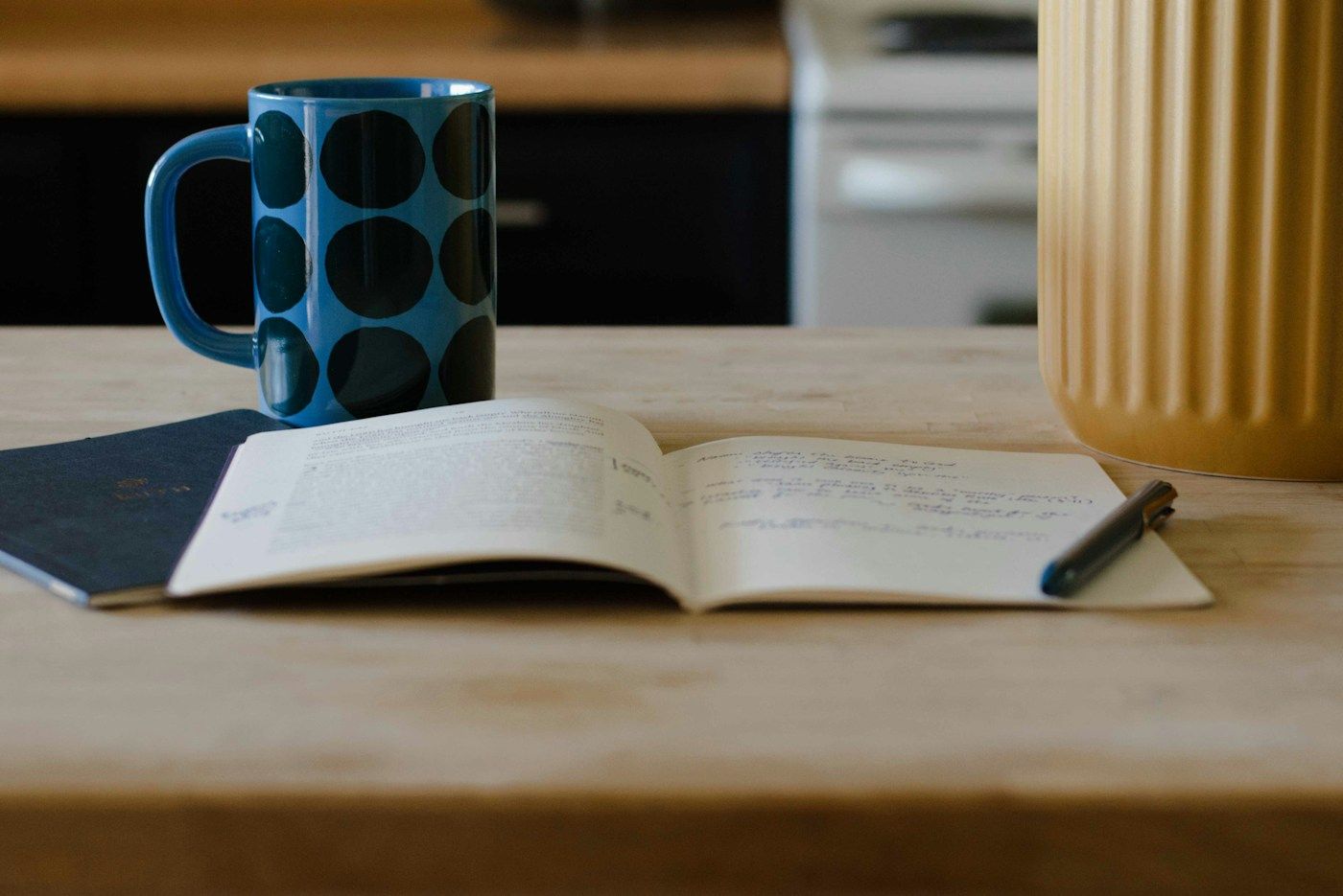 Carnet ouvert, stylo et grande tasse sur une table de cuisine