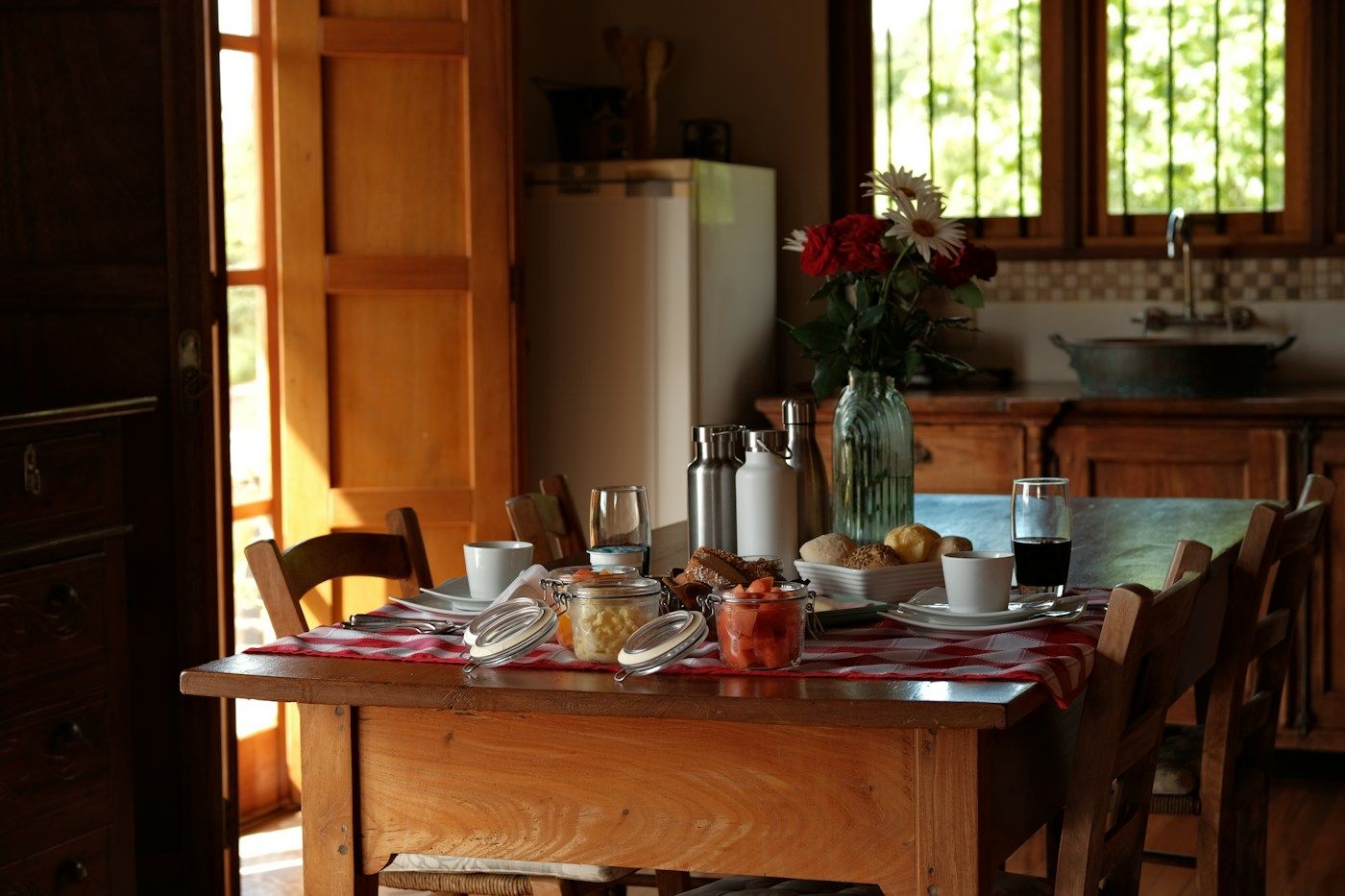 Table de cuisine dressée pour le petit-déjeuner, bouquet de fleurs et lumière du matin